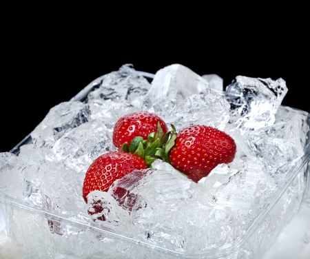 frozen strawberries on ice cubes surface backgroundの写真素材