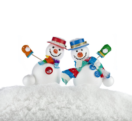Two fun dancing snowmans in a striped scarfs, mittens and cylinder hat isolated on white backgroundの写真素材