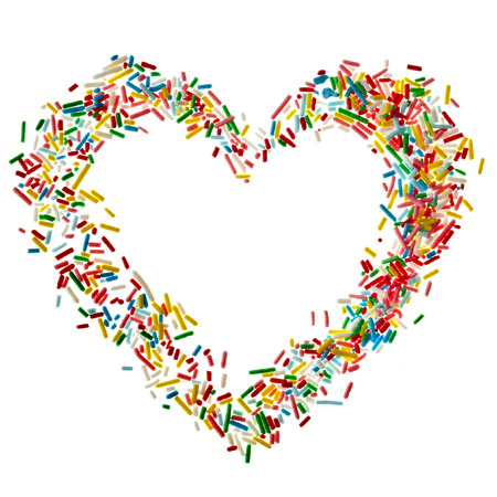 Heart shaped frame card made from colored sprinkles close up isolated on white の写真素材