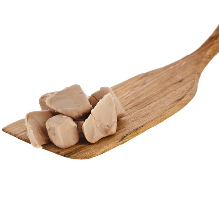 baking ingredient yeast cube block in wooden spoon spatula isolated on white backgroundの写真素材