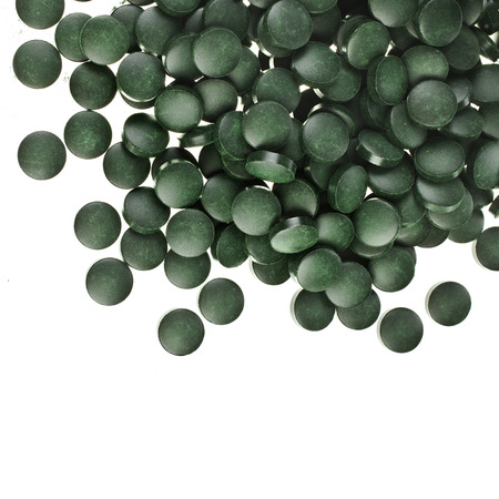 Spirulina tablets algae nutritional supplement heap surface close up top view, isolated on white backgroundの写真素材