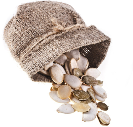 Pumpkin seeds isolated in a burlap sack isolated on a white backgroundの写真素材