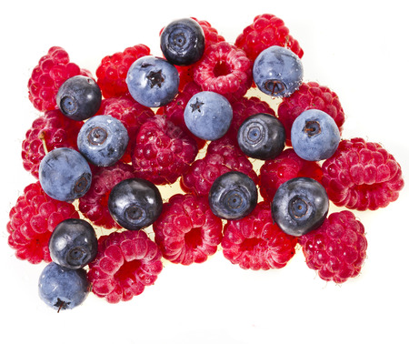 Raspberries and blueberries heap pile isolated on white backgroundの写真素材