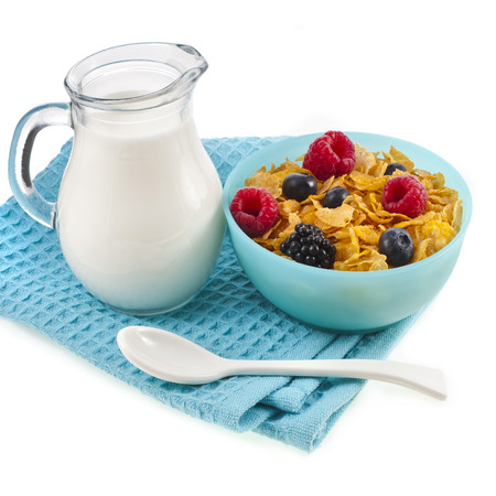 corn flakes with fresh berries and pouring milk isolated on white の写真素材