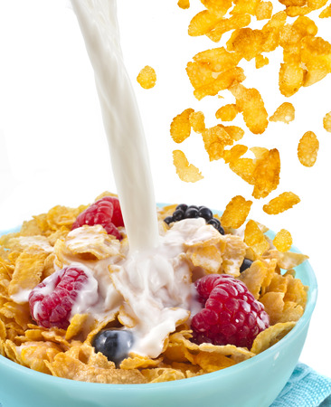 falling corn flakes with fresh berries and pouring milk isolated on white の写真素材