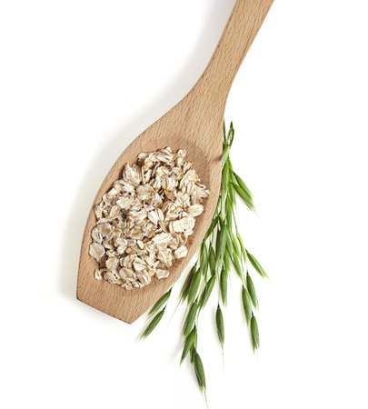 oat seeds close up in wooden spoon surface texture isolated on white backgroundの写真素材