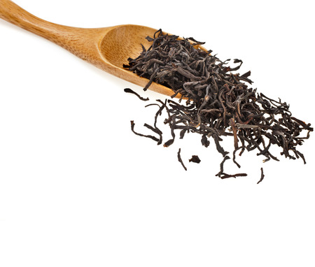 Green tea leaves and wooden spoon isolated on white backgroundの写真素材