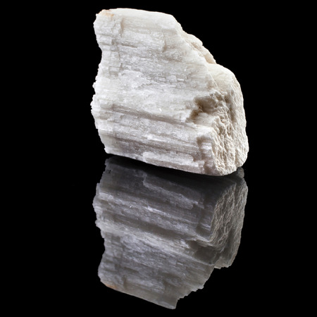 Wollastonite mineral stone close up with reflection on black surface backgroundの写真素材
