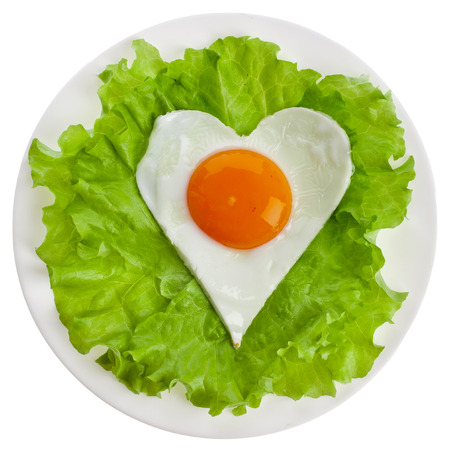 fried egg in shape of heart on a plate top view surface Isolated on white backgroundの写真素材