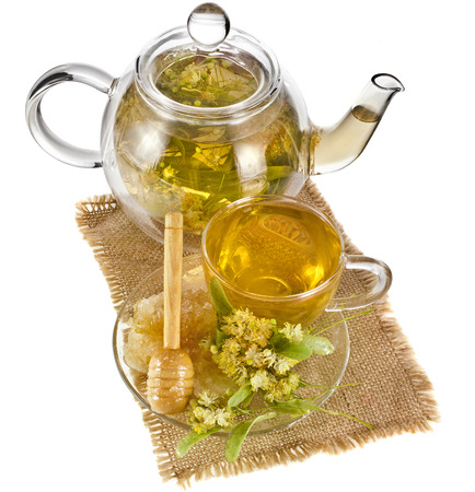 Tea pot with glass tea cup and linden tree bloom isolated on white backgroundの写真素材