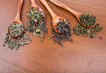 Spoon of mix dried green and black tea leaves on wooden backgroundの写真素材