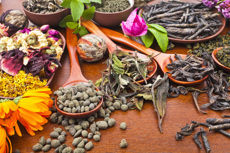 Collection of different dry types tea  green,black, herbal  in wooden spoon on kitchen red wooden table background, top viewの写真素材