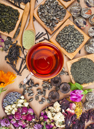 Collection of different dry types tea  green,black, herbal  in wooden spoon on kitchen table background, top viewの写真素材