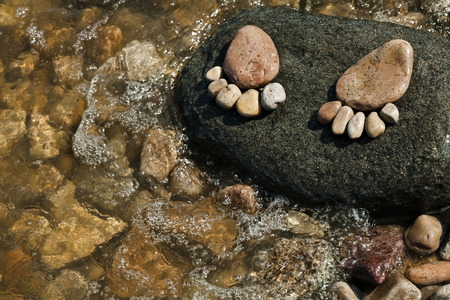 two trace feet made of a pebble stone on the sea wave backdropの写真素材