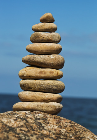Tower pyramid of stone pebbles on background of the sea surface with copy spaceの写真素材