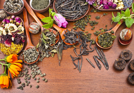 Collection of different types tea  green,black, herbal  in wooden spoon on kitchen red wooden table background, top viewの写真素材