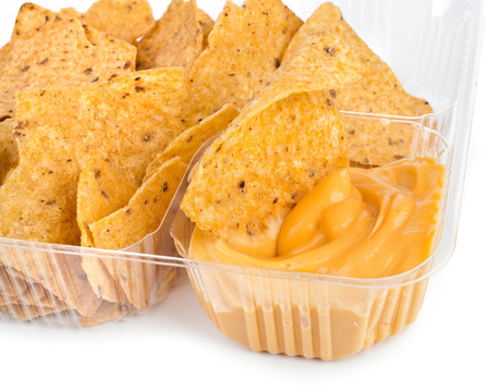 nachos chips with cheese sauce in plastic container on white backgroundの写真素材