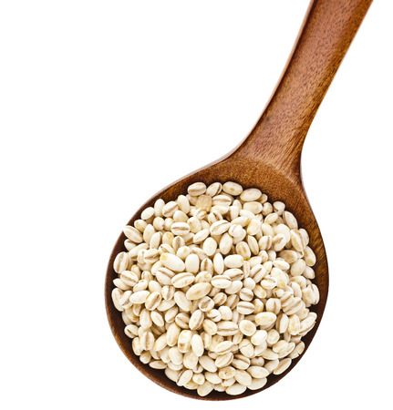 pearl barley in a wooden spoon isolated on white backgroundの写真素材