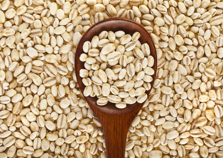 pearl barley with wooden spoon close up surface top view backgroundの写真素材