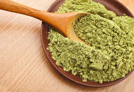 Powdered Green Tea Matcha in spoon on wood table surface close up backgroundの写真素材