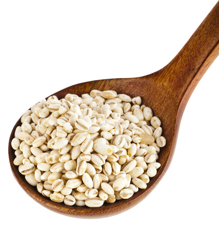 pearl barley in a wooden spoon isolated on white backgroundの写真素材