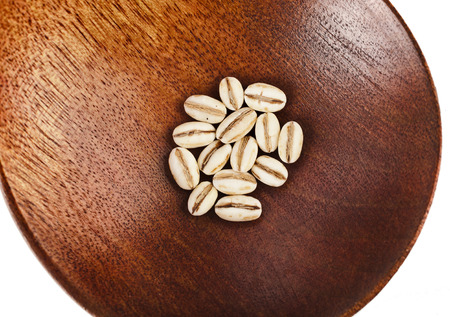 pearl barley in a wooden spoon close up isolated on white backgroundの写真素材
