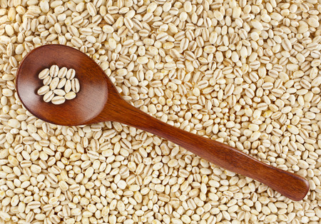 pearl barley with wooden spoon close up surface top view backgroundの写真素材