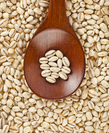 pearl barley with wooden spoon close up surface top view backgroundの写真素材