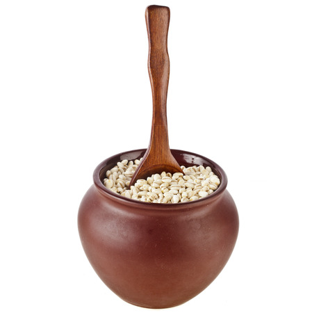 pearl barley porridge in a clay pot with a spoon isolated on white backgroundの写真素材