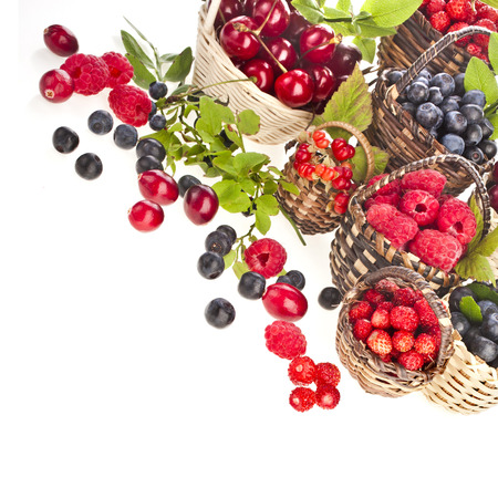Assortment mix of summer fresh forest berries in the basket isolated on white backgroundの写真素材