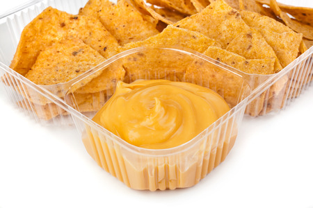 nachos chips with cheese sauce in plastic container on white backgroundの写真素材