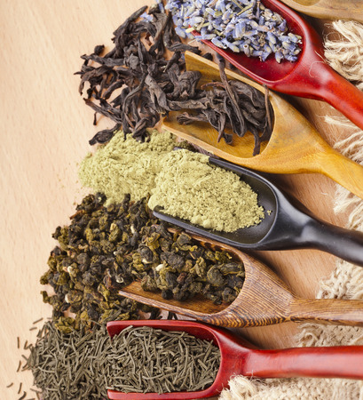 assortment of dry tea in scoops top view close up on wooden backgroundの写真素材