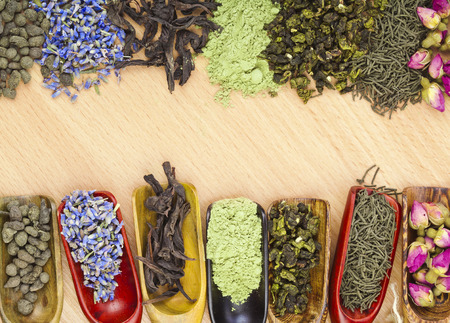 border frame of different dry tea addition in scoops on wooden table background, top viewの写真素材