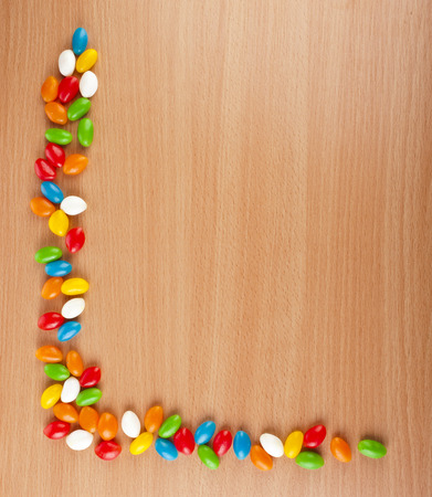 Colored JellyBeans spilled on surface wooden table. top viewの写真素材