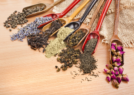 assortment of dry tea in scoops on wooden surface background, top viewの写真素材