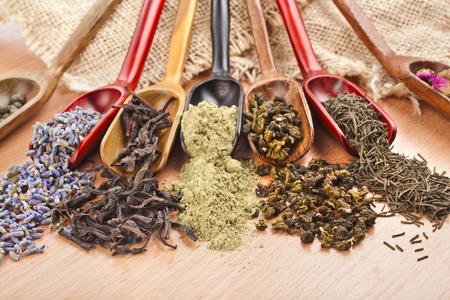 assortment of dry tea in scoops on wooden table background, top viewの写真素材