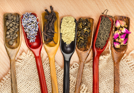 assortment of dry tea in scoops on wooden table background, top viewの写真素材