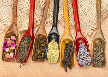 assortment of dry tea in scoops on wooden table background, top viewの写真素材