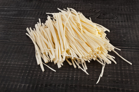 rennet cheese spaghetti on wooden table surfaceの写真素材