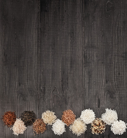 Border of colorful varieties of whole grain rice in a rustic wooden surface backgroundの写真素材