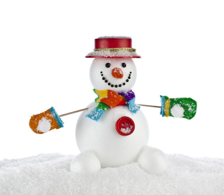Cheerful Christmas snowman in a striped scarf , mittens with red hat , sitting on a snowdrift isolated on white backgroundの写真素材