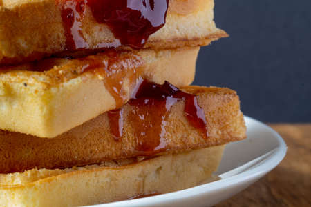 Belgian waffles glass of milk red jam in a white bowl on a brown wooden background sunday breakfast
