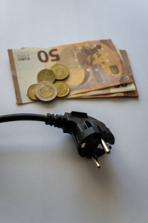 Power plug over euro banknotes on a white surface. Expensive energy and cost of electricity...