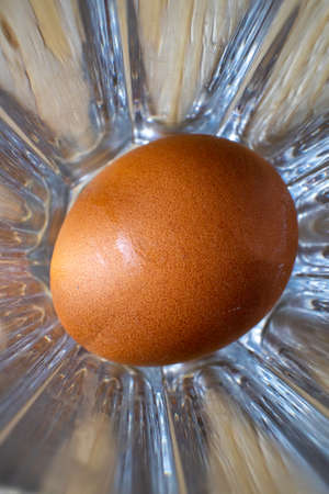Fresh, raw chicken egg in a glass bowl. Brown wood background, top view.の写真素材