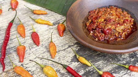 chilli oil in a round bowl surrounded by raw chilli placed on a wooden tableの写真素材