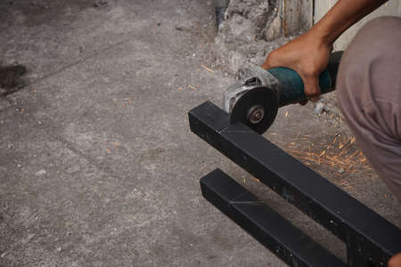construction workers will cut black hollow iron with a grinder, hollow iron is used for building needs.の写真素材