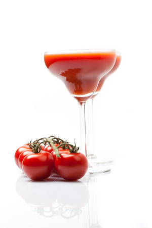 two glasses full of fresh tomato juice, fresh tomatoes beside, white background, isolated, reflection, wide shot,の写真素材
