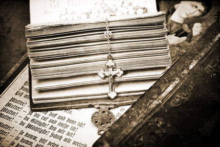 vintage crucifix on opened ancient bible, textured background, sepia,の写真素材