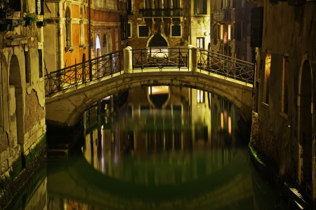 typical canal scene with old bridge in Venice, Italy, at nightの写真素材