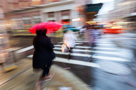picture with creative zoom and blur effect made by camera of people on the move in the city at dawn while it is rainingの写真素材
